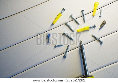 Screws, Dowels And Screwdriver Lie On A Light Wooden Surface. Locksmith Work With Wood.