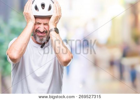 Middle age senior hoary cyclist man wearing bike safety helment isolated background suffering from headache desperate and stressed because pain and migraine. Hands on head.