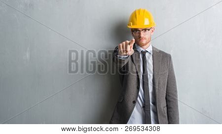 Young redhead man wearing architect outfit and helment pointing with finger to the camera and to you, hand sign, positive and confident gesture from the front