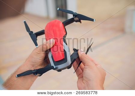Red Drone Catching Control By Man Hands. Lays Out Propellers