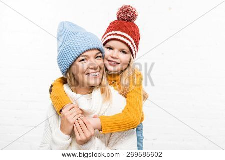 Family Portrait Of Happy Mother And Daughter Looking At Camera In Winter Clothes On White Background
