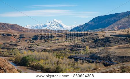 Erzincan, Turkey - August 2018: View Of A Valley With A Train And Railway With Snow Capped Mountains