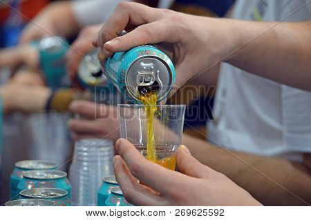 Moscow, Russia - March, 2017: Beer From An Aluminum Can Is Poured Into A Clear Plastic Glass On A Ta