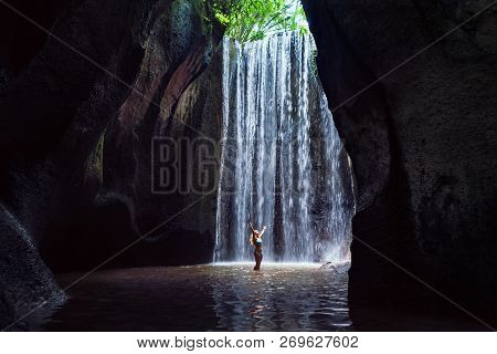 Woman Stand In Underground Cave Pool Under Falling Fresh Water Of Tukad Cepung Waterfall. Nature Day