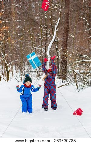 Happy Children In A Winter Snow-covered Forest With Gift Boxes.