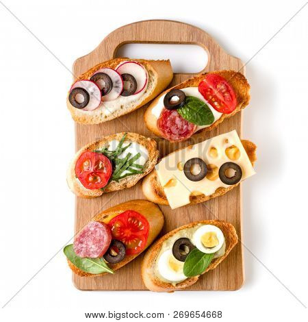 Open faced sandwich canape or crostini on a wooden serving board isolated on white background closeup. Top view.