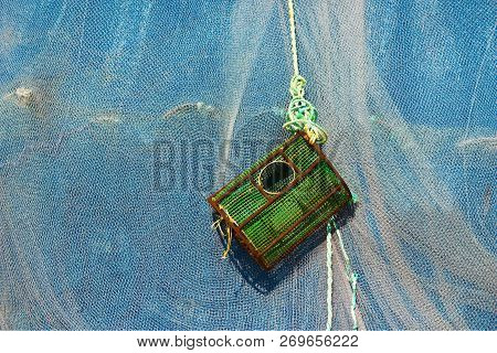 Green Lobster Trap Hanging In Front Of Fishing Net