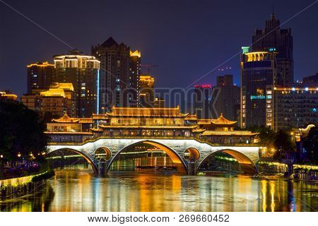 Famous landmark of Chengdu - Anshun bridge over Jin River illuminated at night with modern skyscrapers in background, Chengdu, Sichuan , China