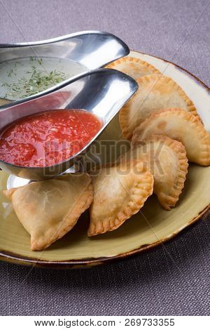 Small Pirogi Stuffed With Meat Served On A Plate With Sauces