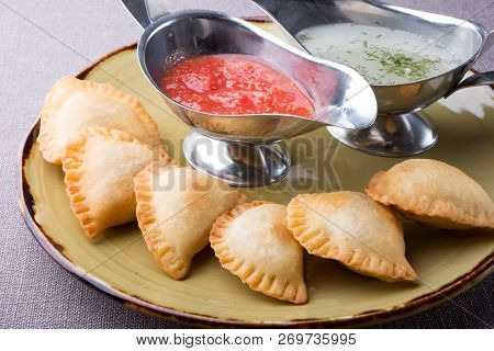 Small Pirogi Stuffed With Meat Served On A Plate With Sauces