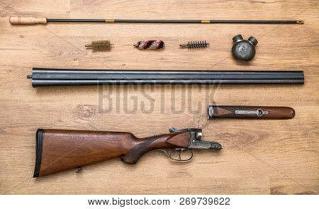 Disassembled Double-barreled Shotgun Parts And Cleaning Kit On The Wooden Background