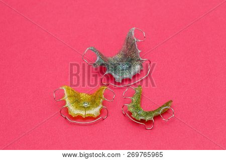 Colorful Dental Braces Or Retainers For Teeth On Pink Background, Closeup
