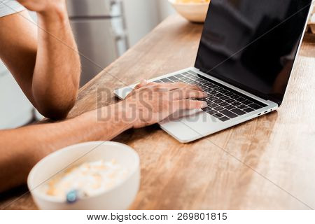 Cropped Shot Of Man Using Laptop With Blank Screen On Kitchen Table At Morning