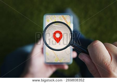 Shot Of Male Hands Holding Magnifying Glass With The Red Icon Of Geo-location And Looking Through It