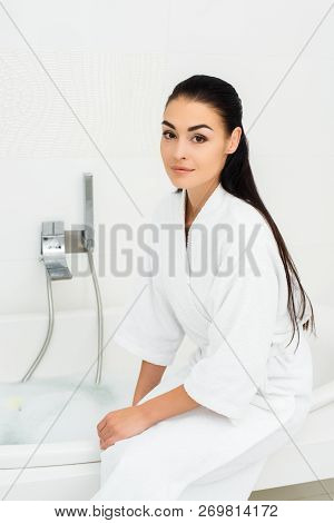 Beautiful Woman Sitting In White Bathrobe In White Bathroom