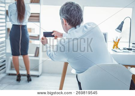 Grey-haired Business Man Photographing His Female Coworker