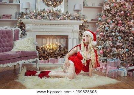 Sexy And Alluring Woman Lying On The Floor Near The Christmas Tree With Gifts.