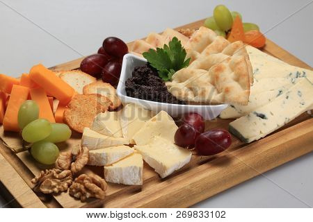 Mix Cheese On A Oard With Some Fruits On The Side