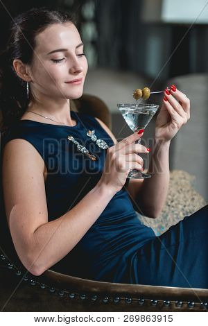 Fashionable Gorgeous Girl In A Dark Blue Dress Drinking Cocktail In A Luxery Hotel Lobby Bar