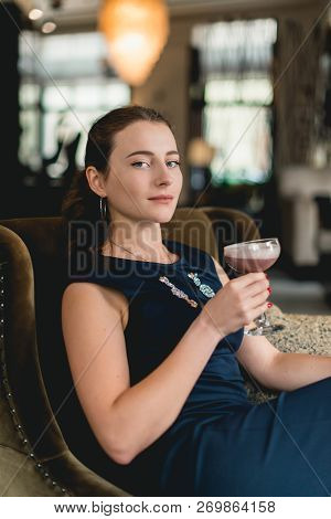 Fashionable Gorgeous Girl In A Dark Blue Dress Drinking Cocktail In A Luxery Hotel Lobby Bar