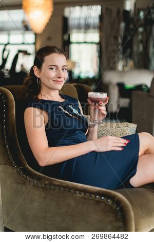 Fashionable Gorgeous Girl In A Dark Blue Dress Drinking Cocktail In A Luxery Hotel Lobby Bar