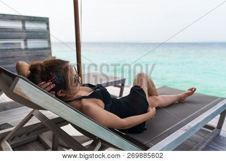 Asian Sexy Woman Sitting On Bedchair Beach At Overwater Villa In Luxury Resport, Vacation Holidays C