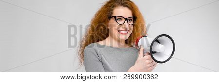 Charming Young Girl With Red Hair. A Young Girl In A Gray Sweater. Young Girl On A Gray Background. 