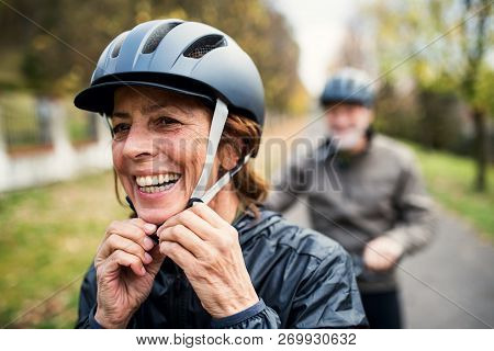 Active Senior Couple With Electrobikes Standing Outdoors On A Road In Nature.