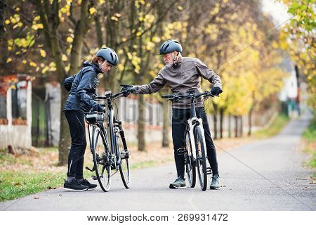 Active Senior Couple With Electrobikes Standing Outdoors On A Road In Nature.