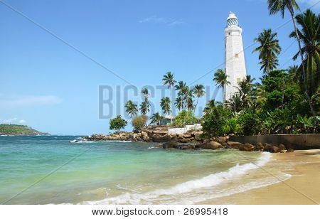 Bellissimo faro bianco Dondra Head, il capo sud dello Sri Lanka - visto dalla spiaggia. Il li