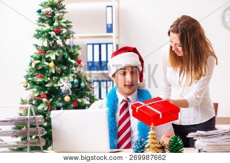 Colleagues exchaing christmas presents in office
