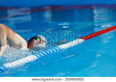 Photo of sports man in blue cap swimming in pool