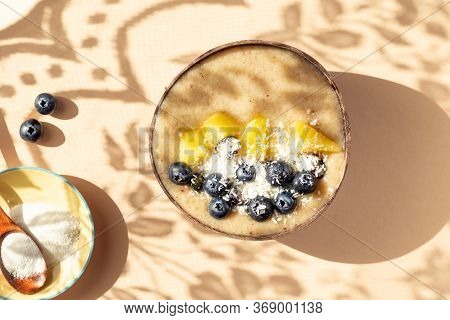 Collagen Powder And Healthy Smoothie From Banana, Pineapple And Gluten Free Oats In The Coconut Shel
