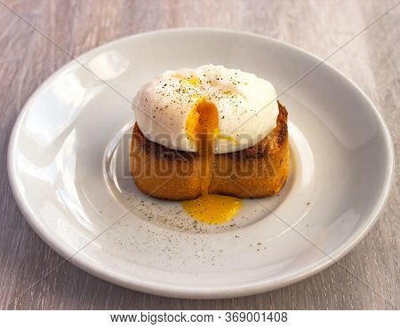 Close-up View Of Tasty Poached Egg With Liquid Yolk With Fresh Green Onion On Toastbread On White Pl