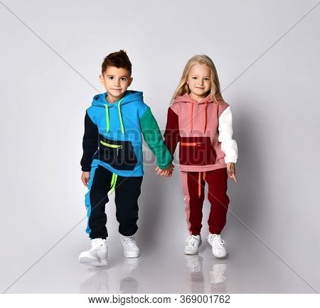 Little Kids In Bright Sportsuits Walking Forward Hand In Hand. Young Athletes, Being Stylish, Friend