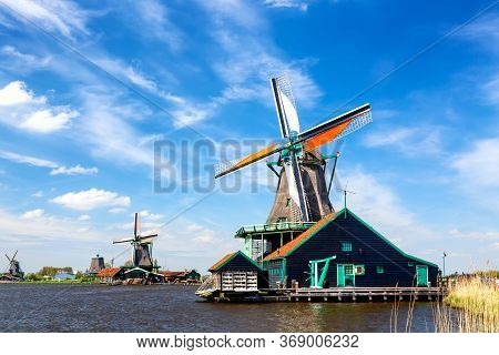 Typical Iconic Landscape In The Netherlands, Europe. Traditional Windmills With A River In Zaanse Sc