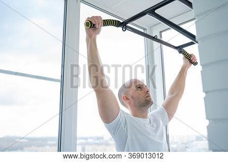 Man Goes In For Sports Doing Pull-up Exercises On Horizontal Bar At His Home