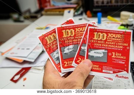 Paris, France - Nov 15, 2019: Man Hand Holding Scratched Lottery Coupons Tickets From Auchan Superma