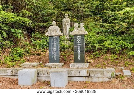 Haeinsa-gil, South Korea; May 26, 2020: Two Stele Grave Markers With Standing Buddha Statue In Mount