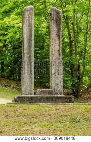 Haeinsa-gil, South Korea; May 26, 2020:two Vertical Stone Columns On Concrete Plinth With Lush Trees