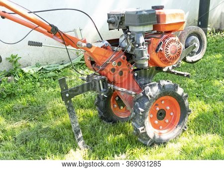 Man Farmer Plows The Land With A Cultivator. Agricultural Machinery: Cultivator For Tillage In The G