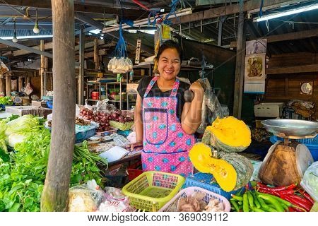 Beautiful Asian Girl Vegetable Seller At The Market Lifts A Dumbbell To Keep Fit. Samui / Tailand - 