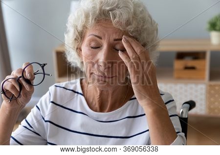 Elderly Woman Sitting In Wheelchair Taking Off Glasses Reduces Eyestrain
