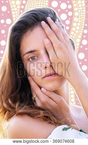 Portrait of a beautiful girl gently touching her face with a fixed gaze into the camera