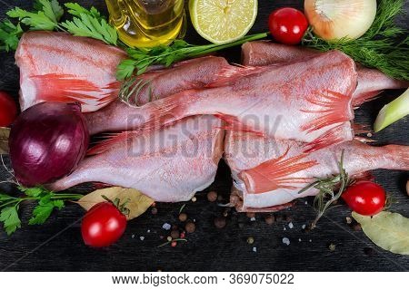 Raw Redfish Carcasses Among The Spices, Vegetables And Greens Close-up