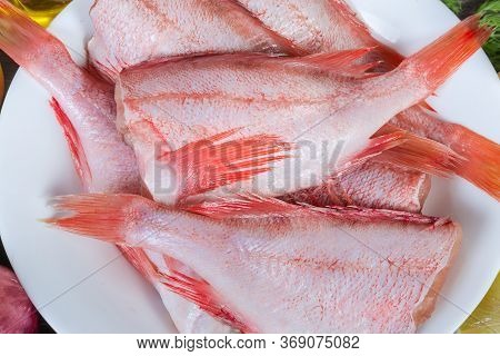 Uncooked Headless Gutted Carcasses Of Redfish Also Known As Ocean Perch On The White Dish, Top View 