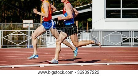 Two Man Middle Distance Runners Run In Stadium. Competition Athletics
