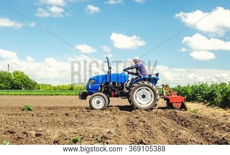 Farmer Drives A Tractor With A Milling Machine. Loosens, Grind And Mix Soil On Plantation Field. Fie