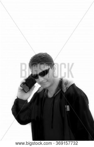 Portrait Shot Of A Hipster Male With A Smile On His Face Talking On Cell Phone Wearing Black Sunglas