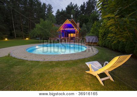 ein Waterpool mit Stuhl in der NÃ¤he von Holzhaus in der Nacht